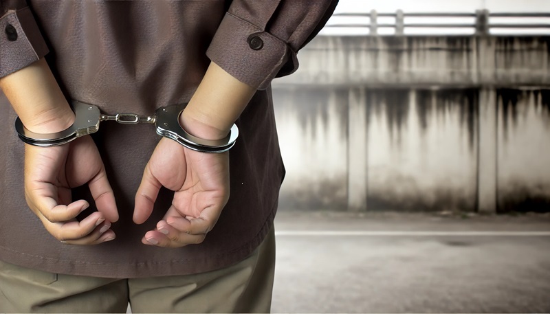 A man with his hands handcuffed behind his back.